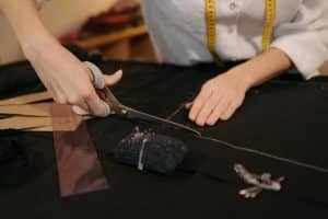 Woman cutting black fabric, symbolizing how to estimate fabric yardage for upholstery